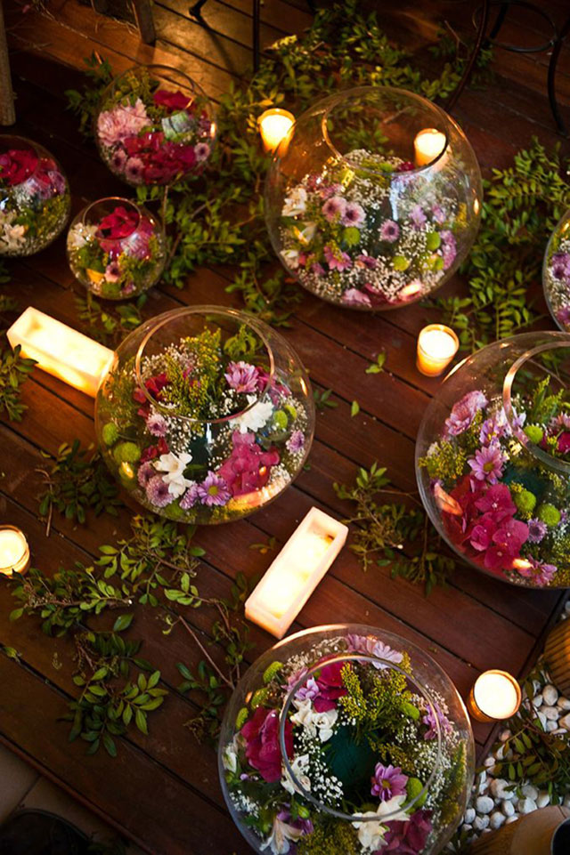 Peceras de vidrio de distintos tamaños con arreglos florales en el interior.