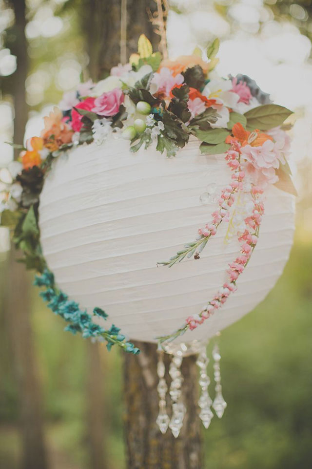 Pantalla de papel blanca decorada con flores y puesta como colgante en el jardín.