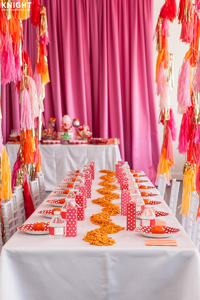 Mesón decorado para fiesta de cumpleaños, con matel blanco y accesorios en colores rosa, rojo y amarillo.