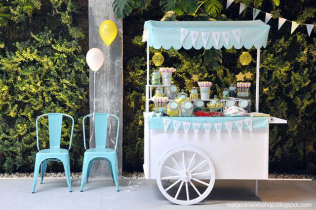 Celebración de primera comunión, con un carrito de helados lleno de dulces en frascos de vidrio y baldes metálicos.