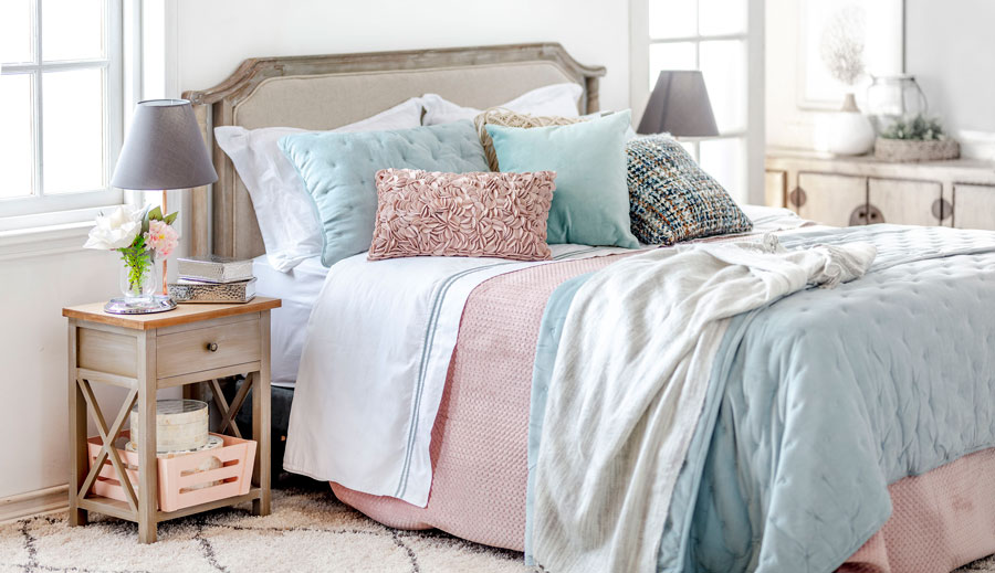 Dormitorio con cama de dos plazas. Cojines de distintos colores siguen todos una paleta de color.