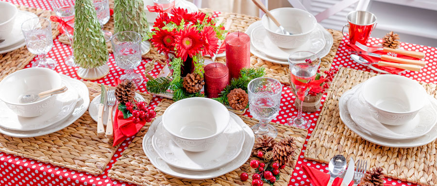 mesa de navidad con individuales de mimbre, vajilla blanca, mantel rojo con puntos blancos