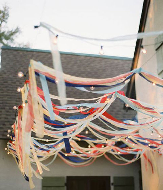 Decoración aérea para el jardín, balcón o terraza. Tiritas de papel blanco, azul y rojo intercaladas con luces.