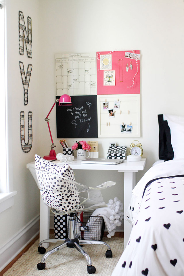 Escritorio junto a la cama. Mesita tipo arrimo de madera blanca, silla de escritorio transparente. En el muro frente al escritorio un mural dividido en cuatro con un calendario, una pizarra, una sección con fotitos colgadas con perritos de ropa y un tablero para pinchar cosas.