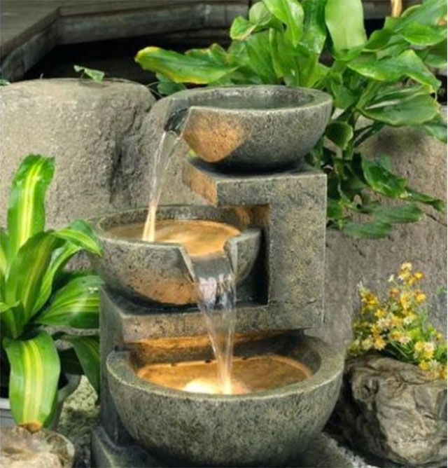 Fuente de agua con vasijas de piedra. Las dos vasijas más grandes iluminadas desde el interior.