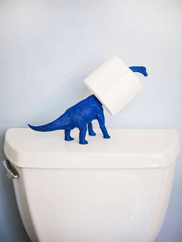 Consigue un dinosaurio plástico grande y de cuello largo. Píntalo con spray y úsalo como porta rollos de papel higiénico.