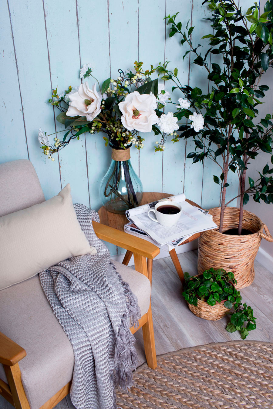 Los colores ice cream, también conocidos como pasteles, combinan perfecto con las fibras naturales, la madera y las plantas. En la imagen se ve el detalle de un sillón junto a una mesa de café de madera y plantas en maceteros de ratán o mimbre.