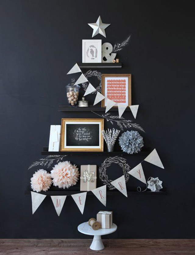 Muro negro con árbol navideño hecho con repisas. Cada repisa, partiendo de la más grande, con decoración en tonos rosa, azul y plateado. Bajo la repisa más grande un pequeño piso blanco y sobre la última repisa y la más pequeña una estrella blanca.