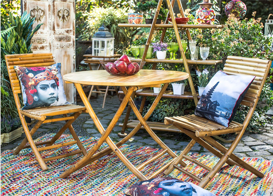 Terraza con mesa y sillas de bambú, con cojines de diseño indú