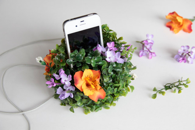 El cargador con el celular y las flores puestas en la bola de pasto. Para asegurarse puedes ponerle silicona caliente y pegarlas.