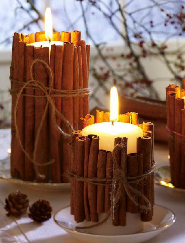 Velas en platitos de loza blanco y cada vela con canela alrededor anudada con cordel.