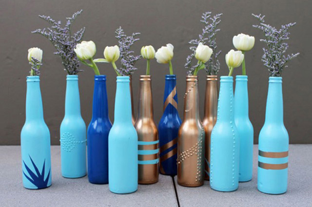 Botellas de vidrio pintadas con color celeste y azul y que sirven de floreros para tulipanes y ramitas de lavanda.