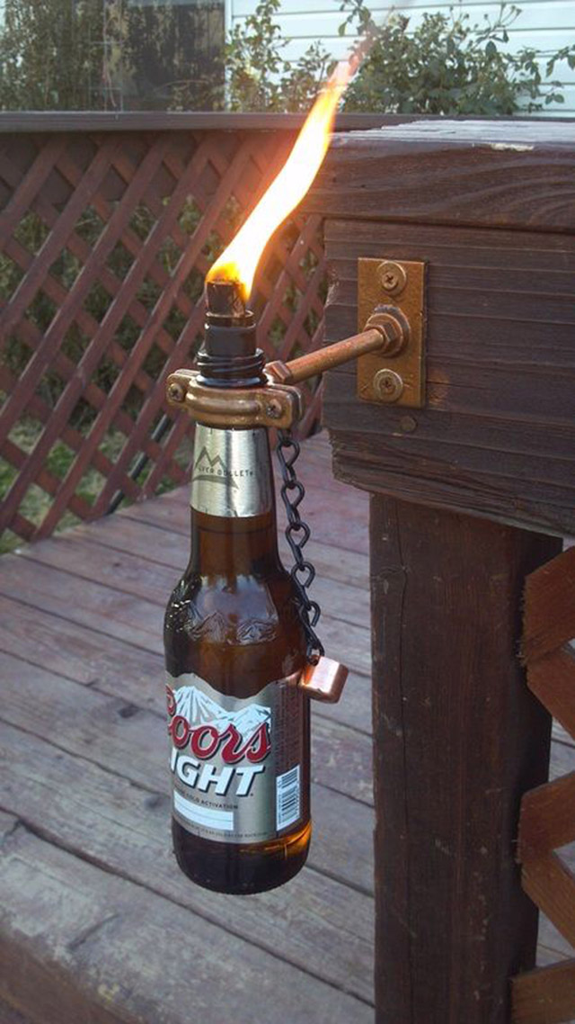 Sujeta desde un mueble de madera, una botella de cerveza que sirve de antorcha.