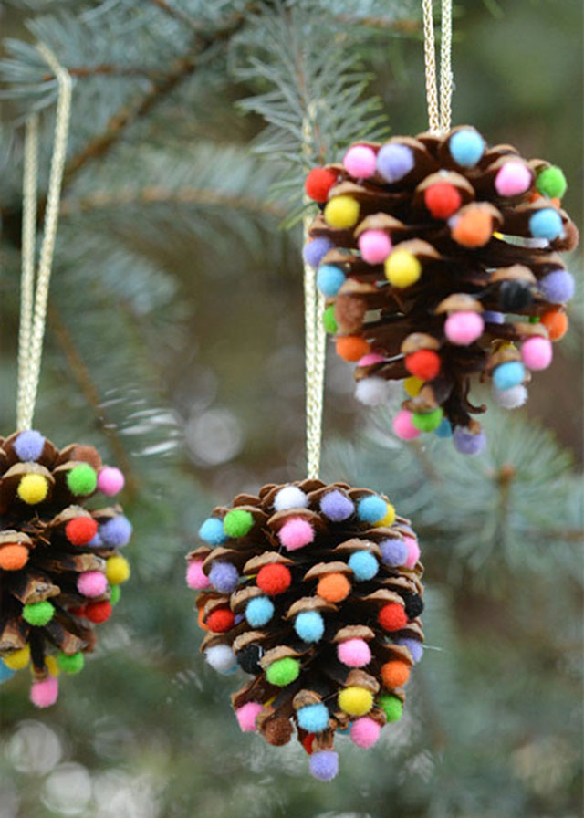 Colgantes de piñas de pino decoradas con pequeños pompones multicolores.