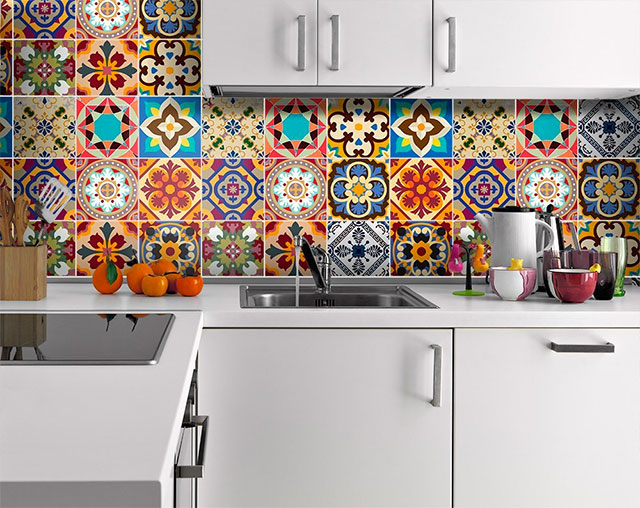 Cocina de muebles blancos de madera laminada y muro con vinilos adhesivos estilo mosaicos multicolor.