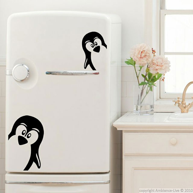 Stickers adhesivos de pingüinos negros sobre refrigerador blanco.