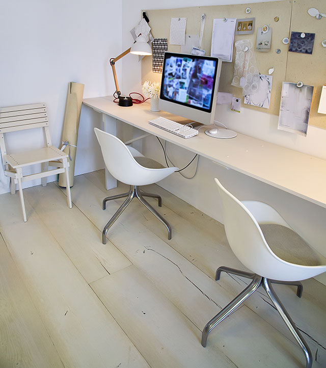 Espacio creativo de diseñador, con dos puestos de trabajo. Tablero de madera en la pared con imágenes y bocetos.