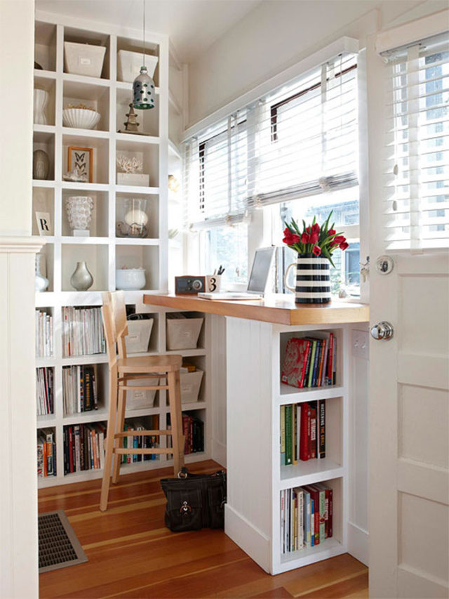 Espacio creativo junto a la ventana. Mesa adosada a la pared, frente a la ventana, con cubuerta de madera, el pie que la sostiene sirve de estante para libros. Al otro costado, la cubierta es la continuación de un estante a muro completo. Una silla taburete de madera para trabajar comodamente.