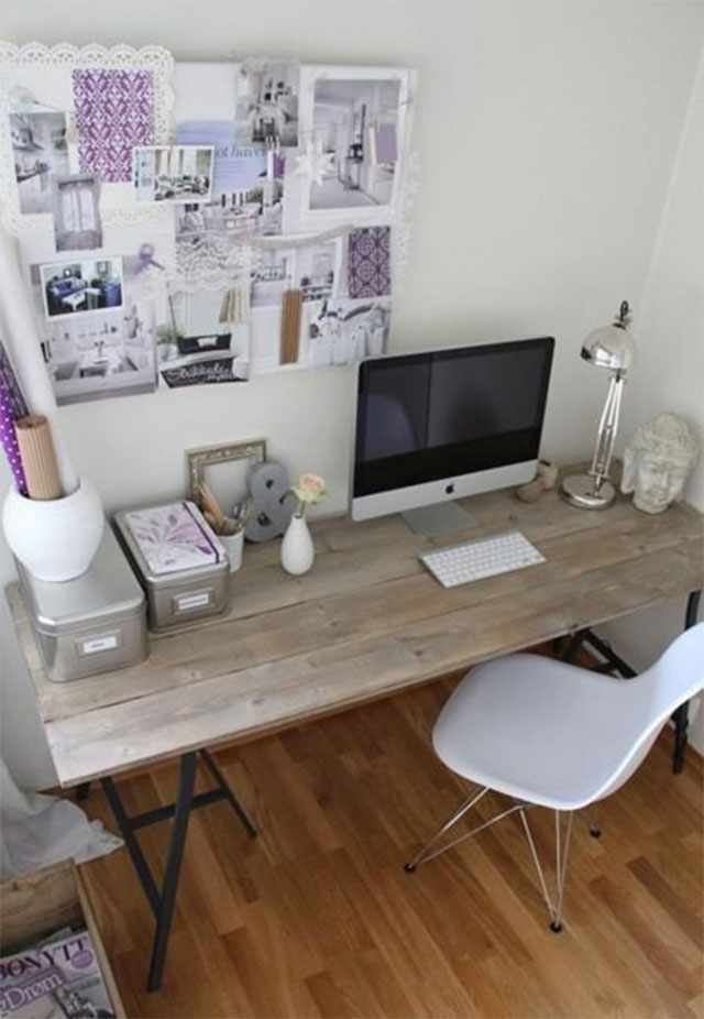 Escritorio con cubierta de madera y silla blanca. Sobre el escritorio todo organizado con cajas y lámpara metálica y accesorios violeta. En la pared, un mural con imágenes en blanco y violeta.