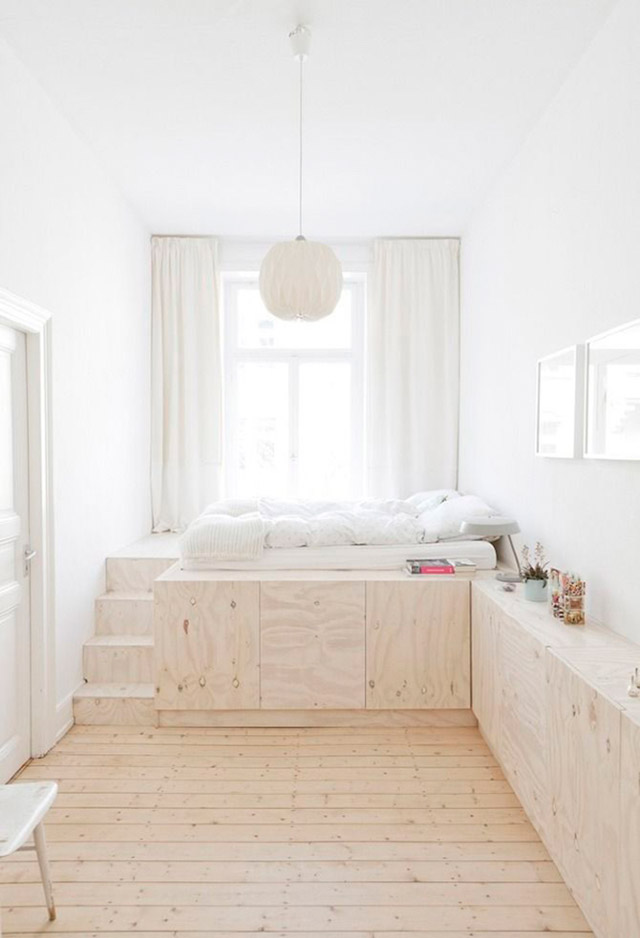 Dormitorio con piso de madera, mueble de madera a lo largo del muro formando un altillo con escalera en donde se encuentra la cama, junto a la ventana.