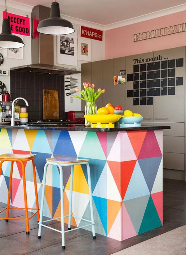 Mesón de cocina americana, con encimera negra y mueble pintado con diseño geométrico multicolor.