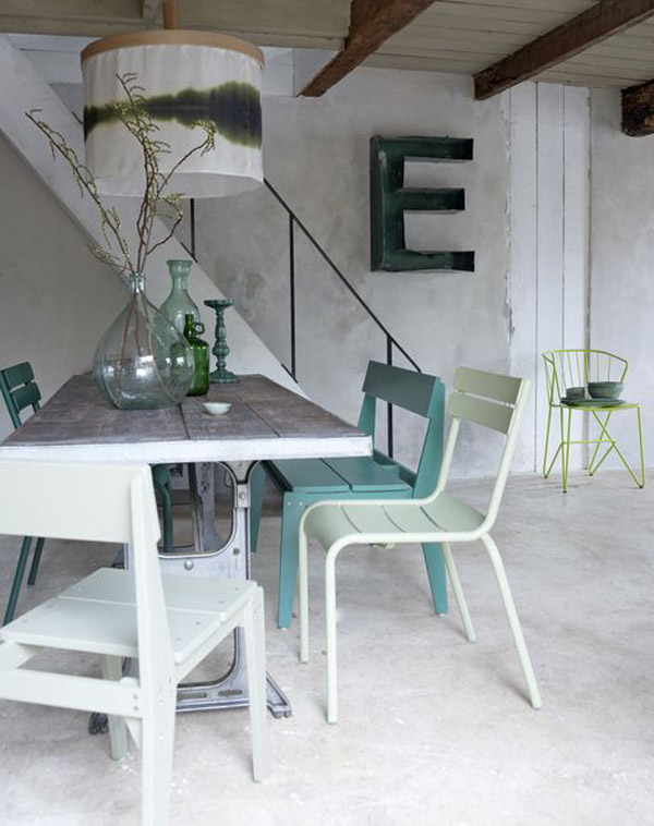 Comedor estilo industrial. En la pared junto a la escalera una letra E en metal desgastado u oxidado y en color verde.